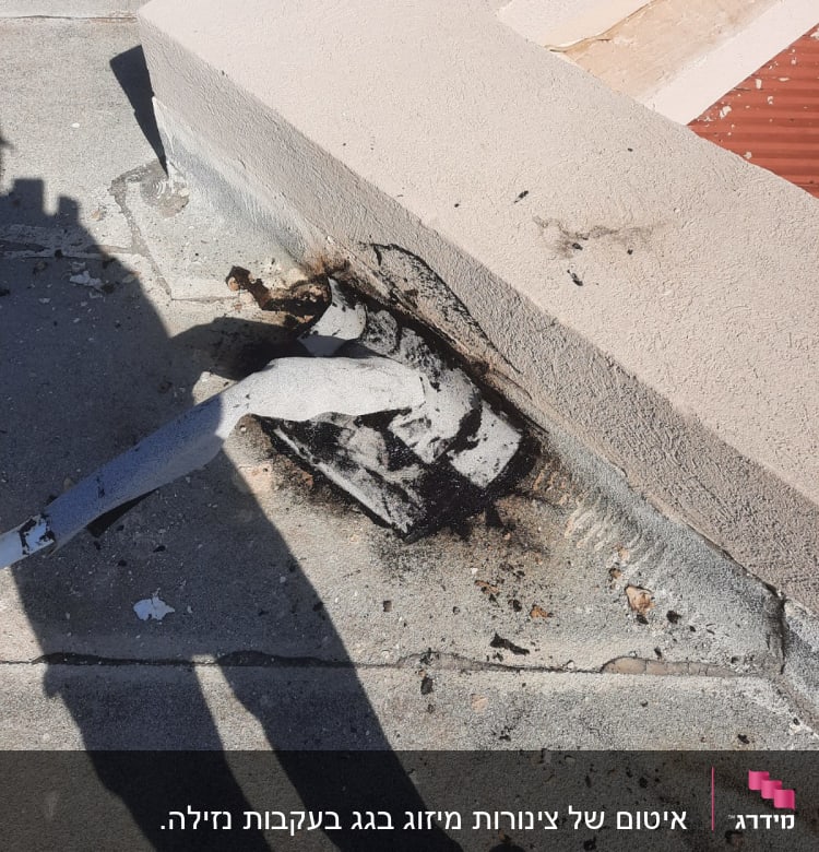 חומר איטום שחור סביב צינור על גג בטון